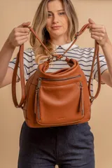 Cartera mochila versátil de cuero sintético con textura granulada, color negro. Cuenta con múltiples bolsillos frontales con cierre, correas ajustables que permiten su uso tanto como cartera de hombro o como mochila, y herrajes metálicos.