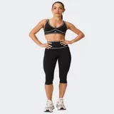 Bra deportivo Fabletics modelo PureLuxe Longline, color negro con ribetes en contraste blancos y logo estampado en el centro.