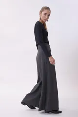 Pantalón de vestir de corte sastrero y pierna ancha (wide leg), confeccionado en tejido de lana gris. Presenta cintura alta con doble botón y pinzas frontales que aportan volumen y caída fluida.