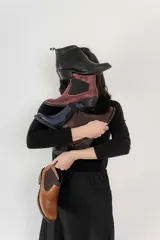 Botín negro de cuero con elásticos laterales, taco bajo y tirador trasero.