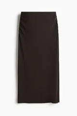 Pollera midi de tiro alto, color marrón oscuro, con diseño drapeado a los lados y abertura lateral en el bajo.