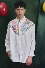 Camisa de corte oversize con mangas largas y puños abotonados. Presenta un diseño bicolor con cuerpo blanco y un canesú delantero con estampado floral multicolor.