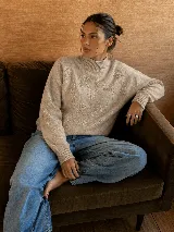 Sweater de punto color beige con cuello alto tipo polera, manga larga y delicado bordado floral al tono en el frente y las mangas.