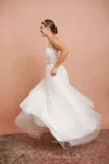 Vestido largo blanco de alta costura, con corset estructurado de tirantes finos con apliques florales y falda amplia de tul con brillo.