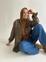 Sobrecamisa de lana con estampado de cuadros en tonos tierra, corte oversize, cuello camisero, cierre frontal de botones y bolsillos delanteros con solapa.