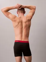 Pack de tres boxers largos Calvin Klein confeccionados en microfibra elástica. Presentan una cintura elástica con el logo de la marca en contraste, disponible en tres colores diferentes: negro con letras blancas, negro con letras negras y negro con letras rojas.