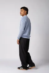Sweater de punto grueso con textura waffle, de calce relajado y cuello redondo. Presenta puños y ruedo acanalados, con un pequeño parche con logo en el puño izquierdo.