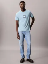 Remera de manga corta y cuello redondo en color celeste, con estampado frontal de logo Calvin Klein en un recuadro central.