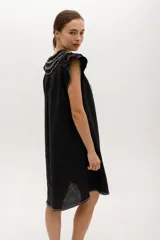Vestido negro de lino, corte suelto, con cuello redondo con volados y mangas cortas con volados.