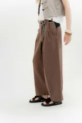 Pantalón blanco de lino y algodón, de tiro medio, con pinzas frontales, pretina ancha en la espalda con cambio de color y vivo en contratono, cortes en la mitad de la pierna de la espalda, cierre frontal con cierre y botón, y bolsillos delanteros.