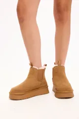 Bota tipo chelsea color camel, con interior forrado en piel sintética, elásticos laterales y plataforma alta con suela dentada.