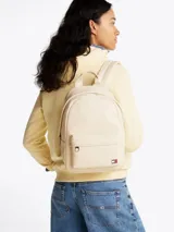 Mochila Tommy Jeans color crema, de poliuretano, con cierre de cremallera, asa superior y correas ajustables y acolchadas. Tiene un compartimento principal, un bolsillo interior de malla y un bolsillo exterior con cremallera.