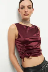 Top sin mangas color borgoña, de satén con cuello redondo y cordones laterales ajustables.