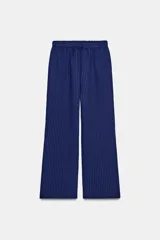 Pantalón de tiro medio con diseño de pierna ancha y textura acanalada. Cuenta con cintura elástica ajustable mediante cordones.