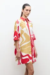 Túnica de corte recto y suelto con estampa floral en tonos de rosado, rojo y amarillo, cuello camisero rojo y mangas cortas holgadas.