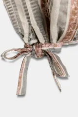 Pantalón bombacho de tiro medio con estampado de rayas verticales en tonos tierra y beige. Presenta aplicación de lentejuelas, cinturón del mismo tejido, forro interior tipo shorts y bajo acabado en puño con lazada. Cierre lateral con cremallera oculta.