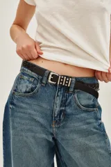 Cinturón de cuero vacuno trenzado en color negro, con hebilla metálica plateada de diseño rectangular con detalles de tachas.