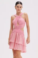Vestido corto de chifón color rosado, con escote halter cruzado, aberturas frontales y laterales en la cintura, y falda corta con volados escalonados.