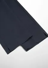 Pantalón de vestir azul marino, de corte skinny y diseño crop de tiro medio, con trabillas, bolsillos laterales y cierre frontal de cremallera y botón.