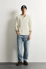 Jeans de corte slim cropped confeccionados en denim de algodón rígido con efecto lavado. Presentan tiro medio, cierre frontal con cremallera y botón, y diseño clásico de cinco bolsillos.