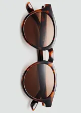 Lentes de sol circulares con montura de carey y cristales marrones.