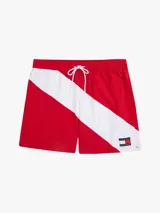Short de baño rojo con cintura elástica ajustable con cordón, corte amplio y logo de Tommy Hilfiger en la pierna. Presenta una franja diagonal blanca con el logo de la marca en la parte inferior.