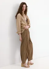 Pantalón marrón de corte recto, con cintura ajustable elastizada y cordón, y detalle de franja lateral bordada con diseño calado.