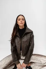 Chaqueta bomber de cuero marrón con efecto vintage, cierre frontal con cremallera, cuello alto y mangas largas.