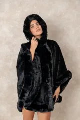 Capa de piel sintética en color negro, con diseño holgado, capucha integrada y bordes con textura de pelo largo.