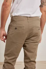 Pantalón de vestir verde oliva, de corte slim fit, sin pinzas, con bolsillos laterales y traseros. Se ajusta a la cintura con cinturón de cuero marrón.