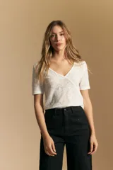 Top de manga corta confeccionado en tejido jacquard con textura en relieve. Presenta escote en V y un diseño frontal con líneas diagonales que crean un efecto cruzado.