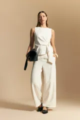 Pantalón ancho de tiro alto, color blanco roto con finas rayas verticales en color beige/marrón. Presenta un detalle de nudo o lazo en la cintura.