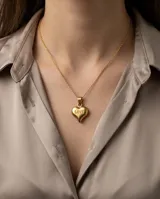 Collar de cadena fina con dije de corazón en relieve grabado con la palabra LOVE, acabado en tono dorado.