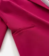 Blazer sastre de corte alargado y diseño minimalista sin botones. Presenta cuello con solapas clásicas, mangas largas y bolsillos laterales tipo vivo. Confeccionado en tejido estructurado con forro interior.