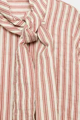 Camisa de rayas rojas y blancas, cuello redondo con lazada integrada y manga larga.