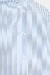 Camisa Zara Woman Collection de algodón con estampado de rayas verticales blancas y celestes. Presenta cuello perkins, mangas tres cuartos y un diseño asimétrico con cierre frontal cruzado mediante botones.