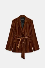 Blazer de terciopelo color marrón, con cuello solapa, manga larga y cierre frontal cruzado con botones. Incluye bolsillos con solapa en el delantero y un cinturón del mismo tejido para ajustar a la cintura.