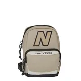 Bandolera tipo mochila pequeña New Balance, color beige con detalles en negro y blanco. Presenta el logo 'N' grande en el frente y el nombre de la marca en el bolsillo delantero. Cuenta con dos compartimentos con cierre y correa ajustable.