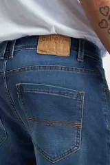 Jean de calce recto, color azul medio, con bolsillos delanteros y traseros.