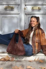 Cartera tipo hobo de gamuza negra, con diseño minimalista y asa integrada.