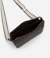 Bolso tipo bandolera de color marrón oscuro, con textura de cuero sintético (PU) y patrón geométrico acolchado en la parte frontal. Cuenta con herrajes dorados, cierre superior y una correa ancha de tela bicolor (beige y marrón) ajustable.