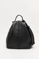 Mochila negra de símil cuero texturizado, con asa superior, tiras regulables para la espalda y cierre principal metálico. Presenta un detalle trenzado vertical en el frente y un accesorio de flecos con una cuenta redonda.