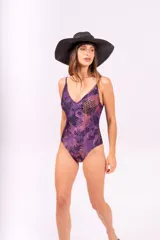 Malla enteriza con estampado abstracto en tonos violeta, negro y naranja. Tiene breteles finos y espalda baja.