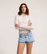 Short de jeans de tiro bajo, color celeste claro desgastado, con trabilla, cierre tradicional y bolsillos. Incluye una cadena decorativa con dijes de estrellas.