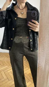 Camisa negra de cuero sintético con botones dorados.