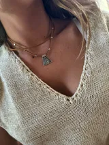 Gargantilla de cuero marrón con dije triangular plateado.