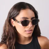 Lentes de sol con armazón metálico dorado y diseño geométrico, con patillas decoradas y cristales oscuros con protección UV400.