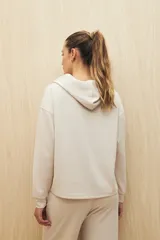 Canguro color beige de la línea Essence, con capucha, corte amplio y detalle de recorte frontal.