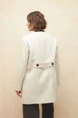 Tapado largo color crema, de paño, con cuello a la base y botones redondos veteados.