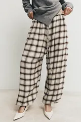 Pantalón bombacho de tiro alto con estampado de cuadros en tonos crudo y marrón. Presenta cintura elástica ajustable con cordón y bajos elásticos.